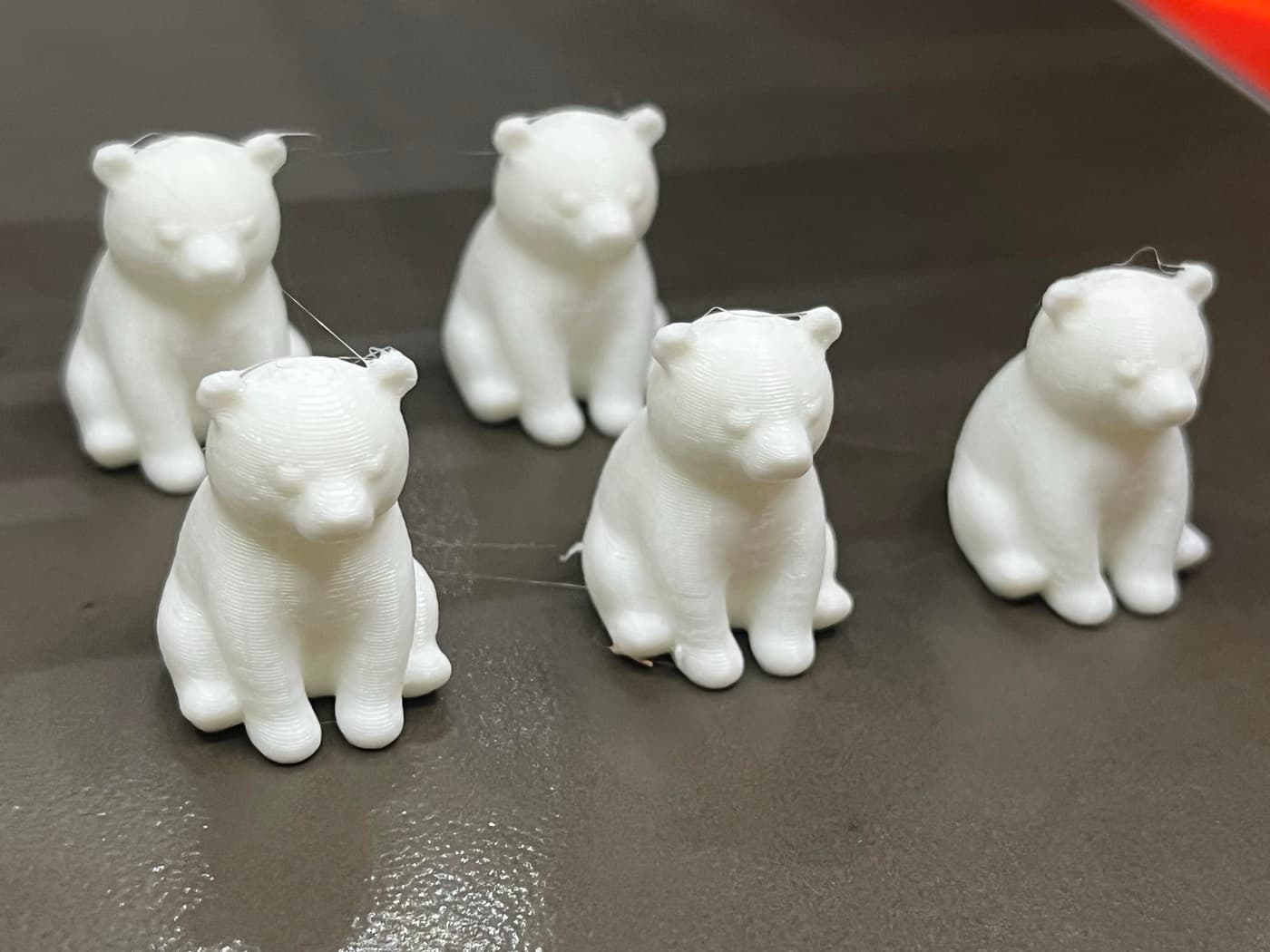 A group of five small, white bear figurines sitting on a dark surface.