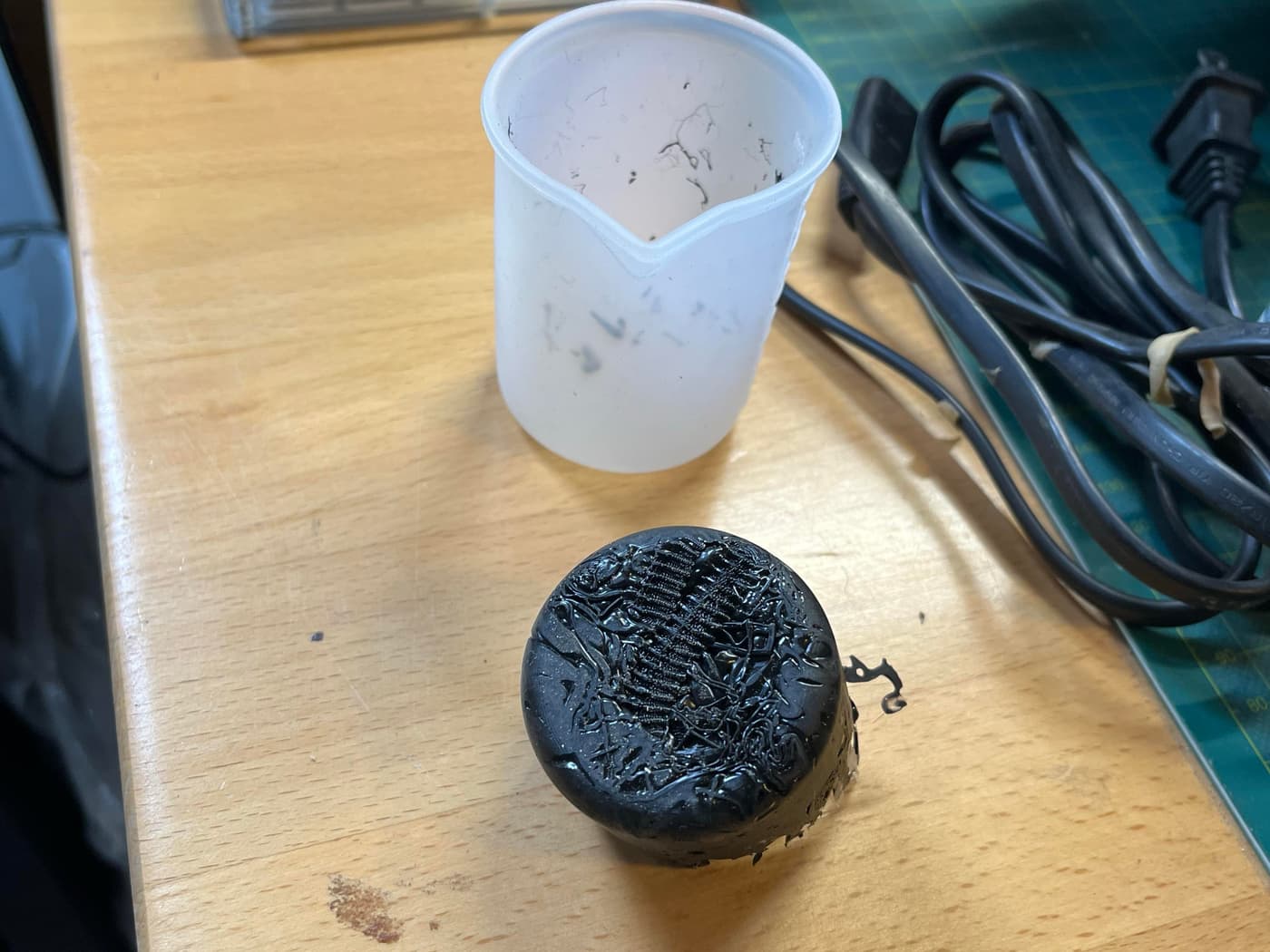 Another angle of the melted plastic artifact in a silicone cup