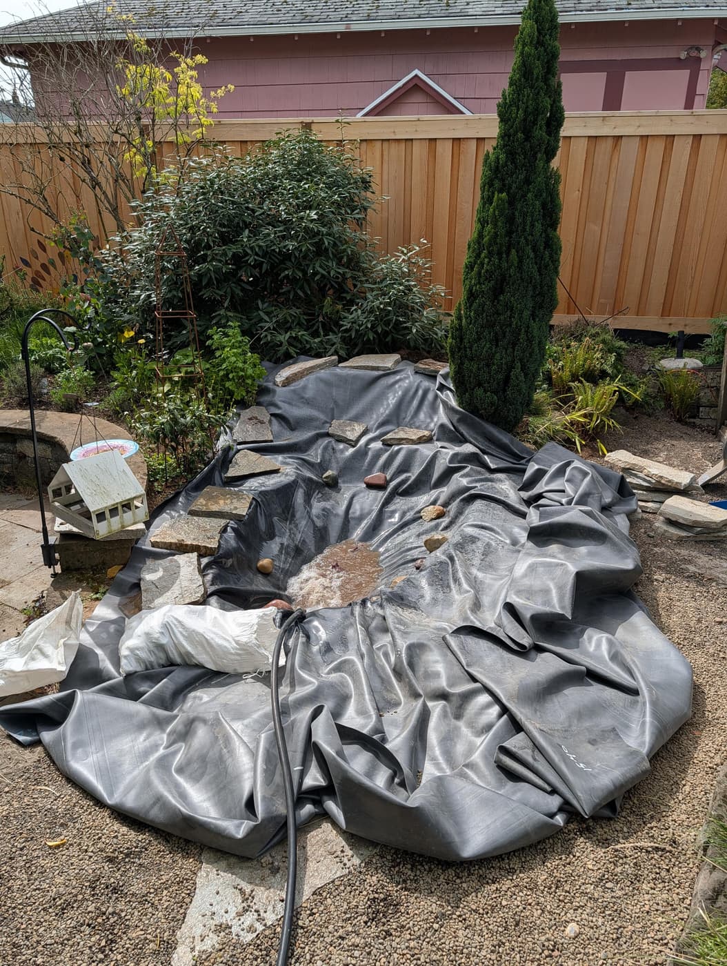 Photo of a large sheet of EPDM rubber draped into a bathtub-sized hole dug in the dirt of a backyard