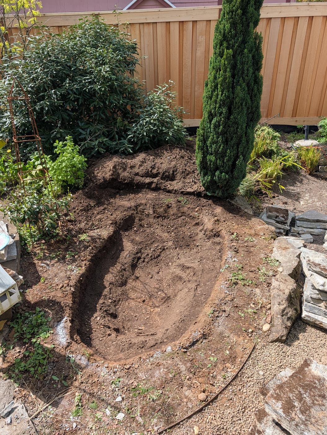 Photo of a bathtub-sized hole dug in the dirt of a backyard