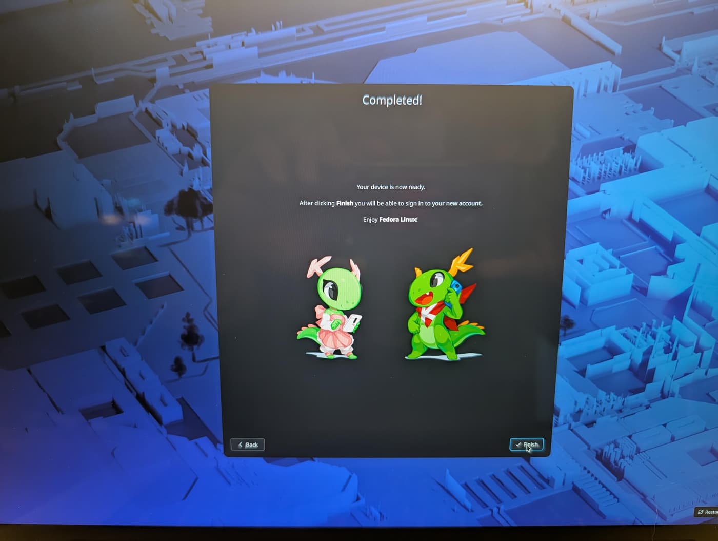 The final screen of a Fedora install, showing a "Completed!" dialog with two cartoon dragon mascots