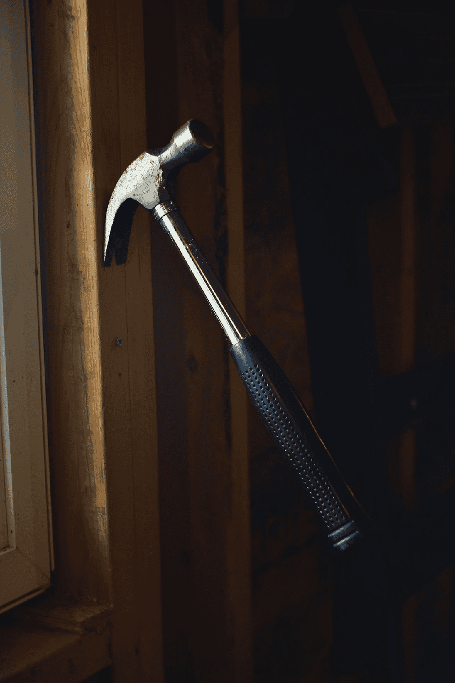A black and silver steel claw hammer resting on wood